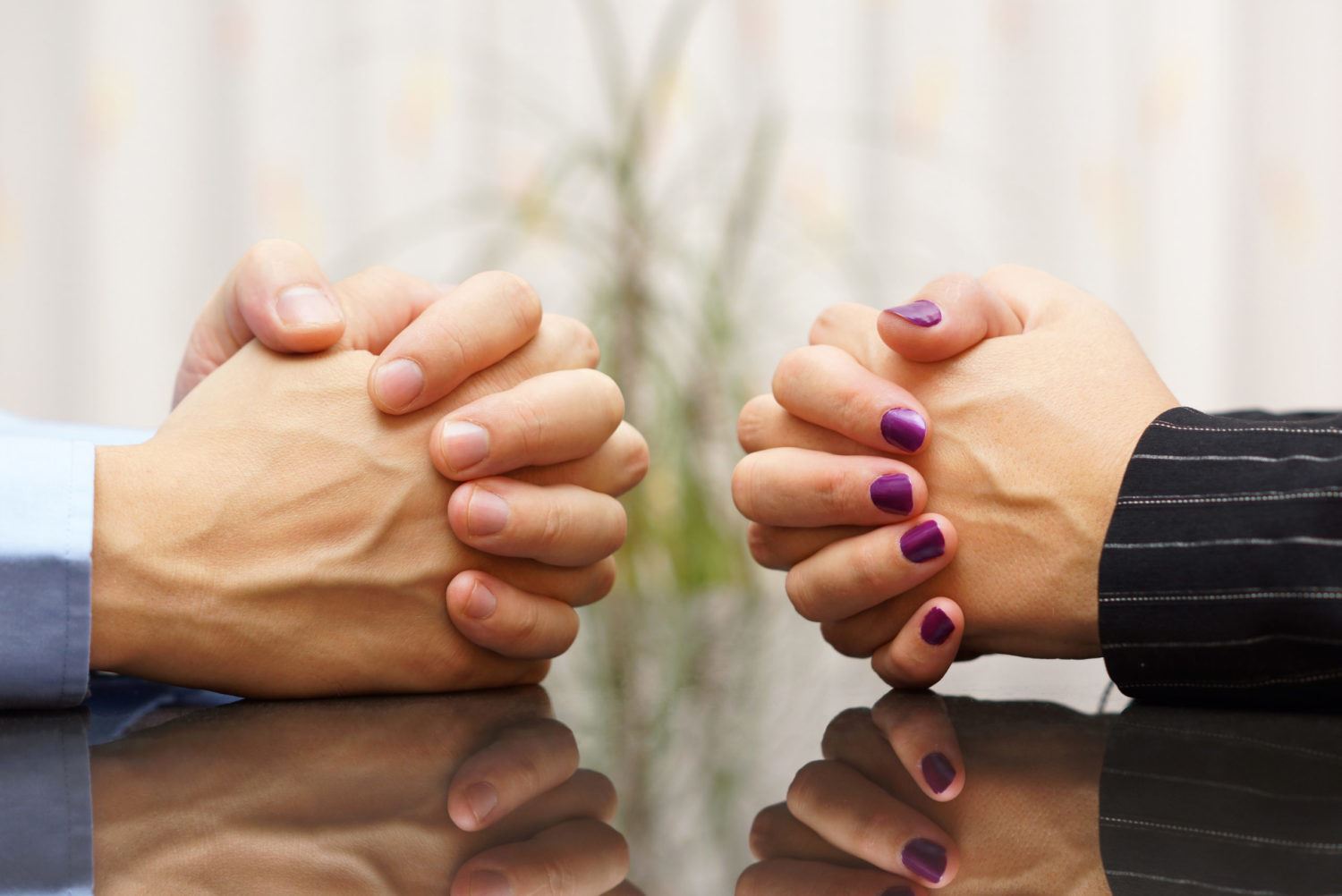 2 people with hands folded on table